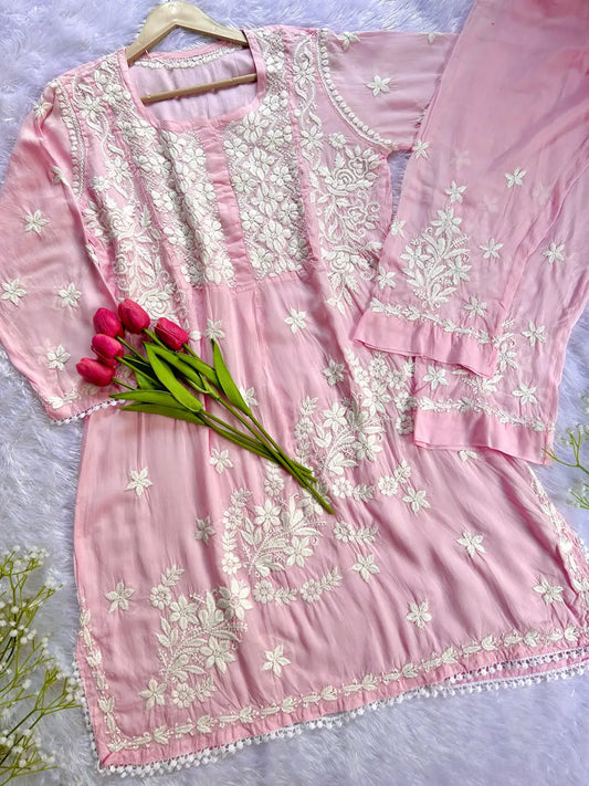 Pink embroidered dress with white floral patterns on a light background