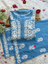 Powder blue chikankari rayon kurta set with intricate white floral embroidery, displayed on a white fur background with decorative red rose petals and artificial tulips. The set is from Hayat&